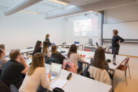 Lärare som föreläser framför en grupp studenter.